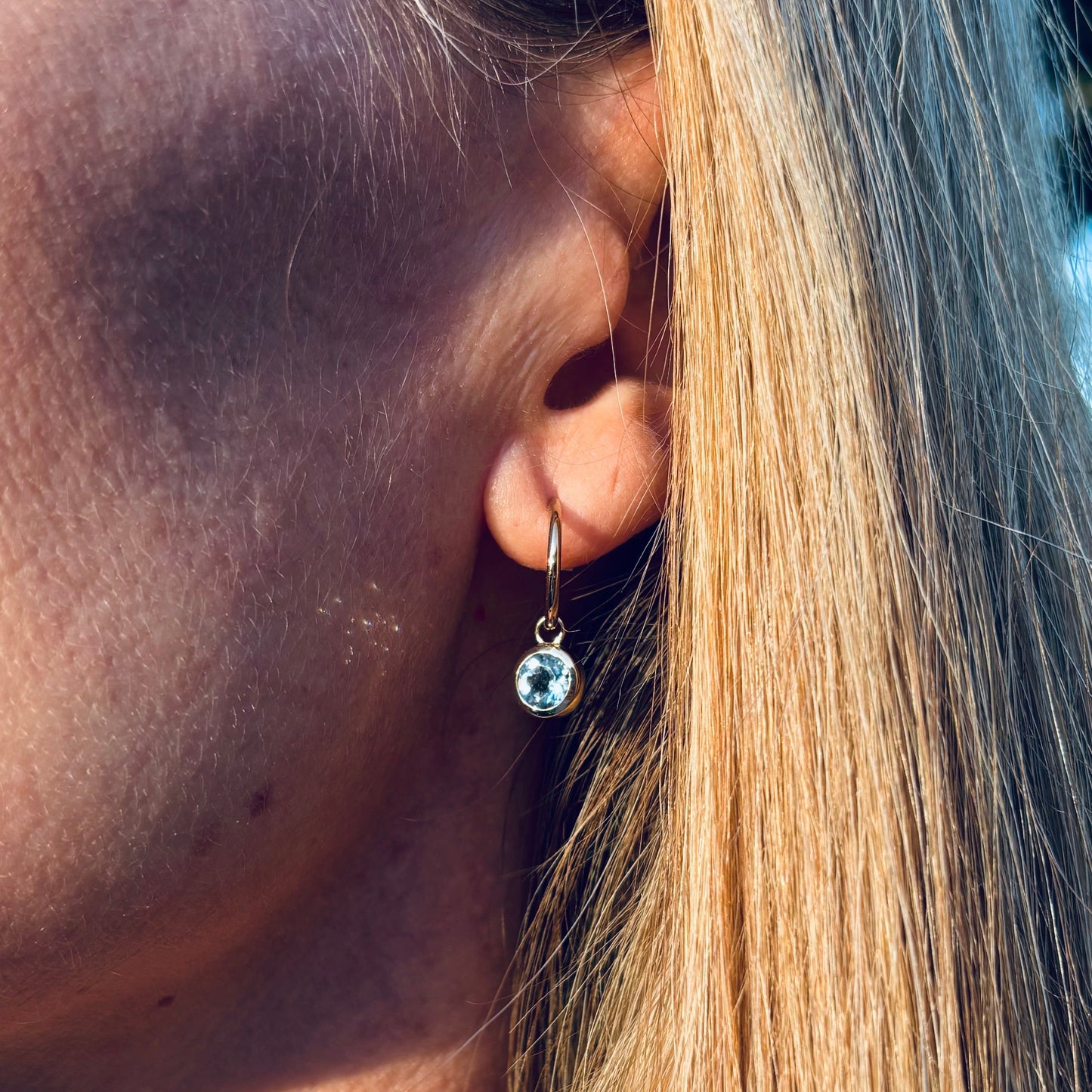 A woman wearing gold aquamarine hop earrings