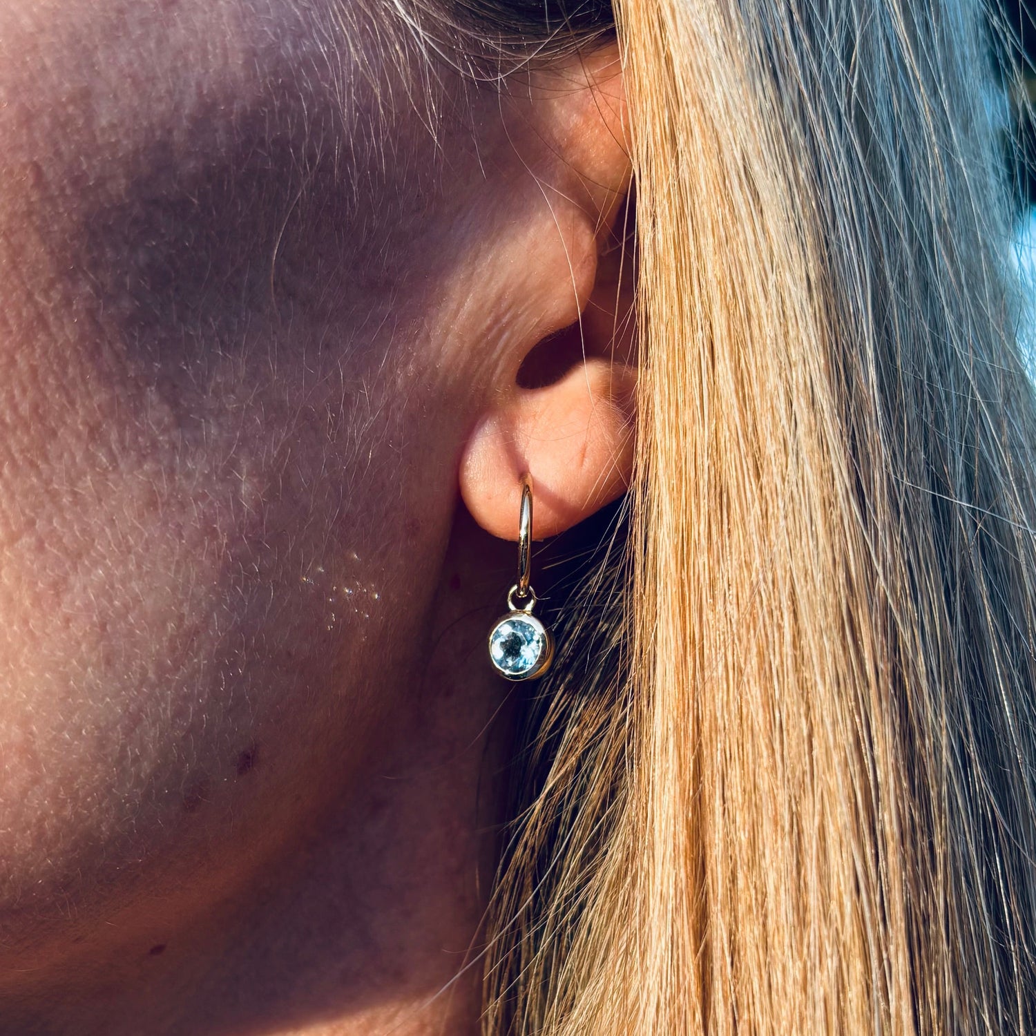 A woman wearing gold aquamarine hop earrings