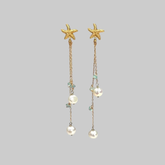 Starfish and pearl drop earrings on a light blue background