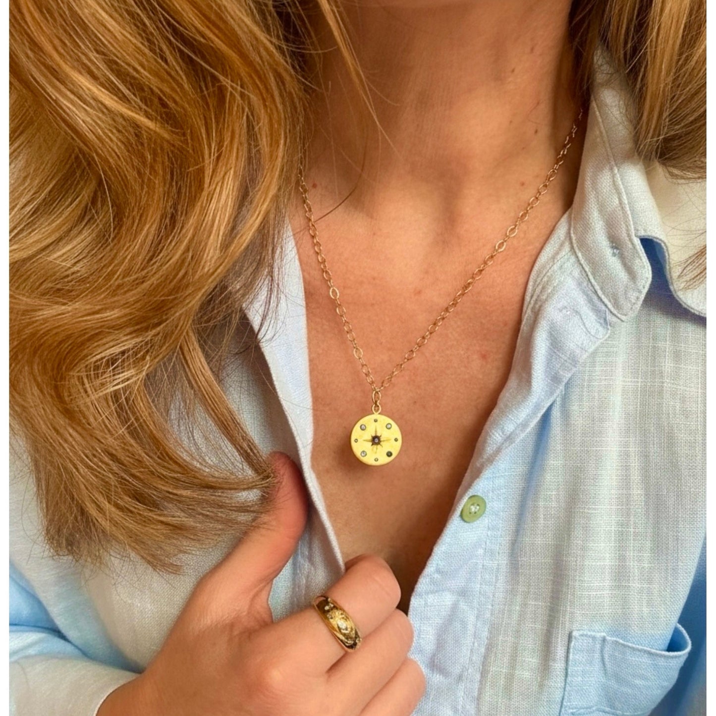 Person wearing a gold medallio necklace with Sapphires