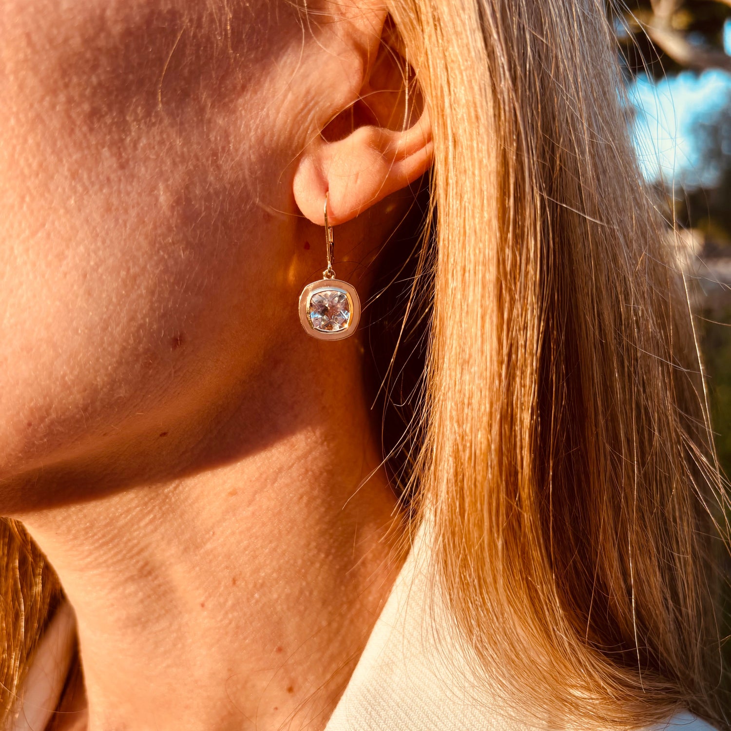 Close-up of a person wearing a diamond earring outdoors