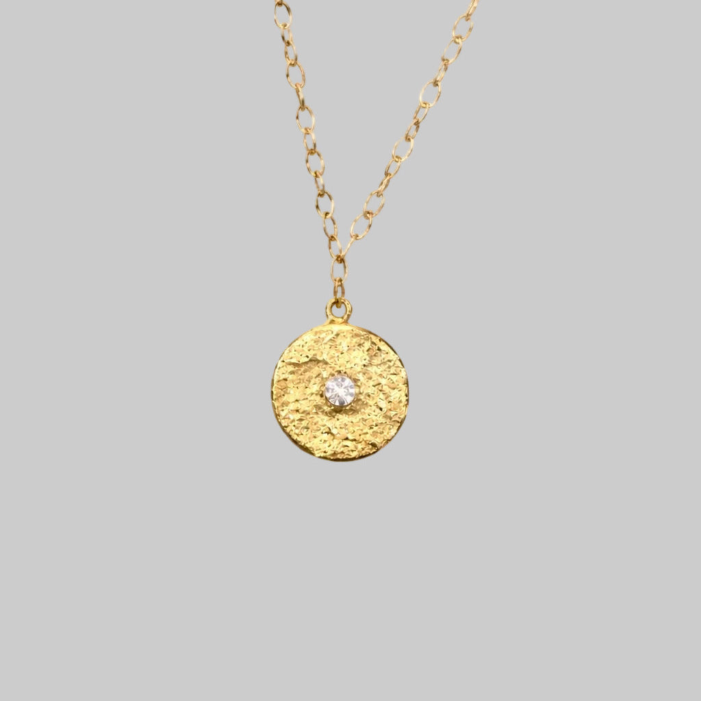 Textured Gold medallion with white topaz in the center 