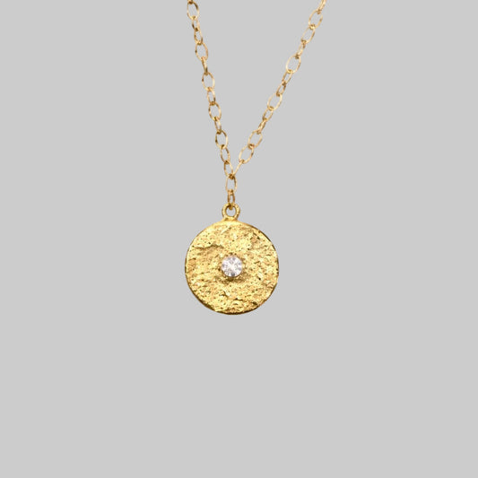 Textured Gold medallion with white topaz in the center 
