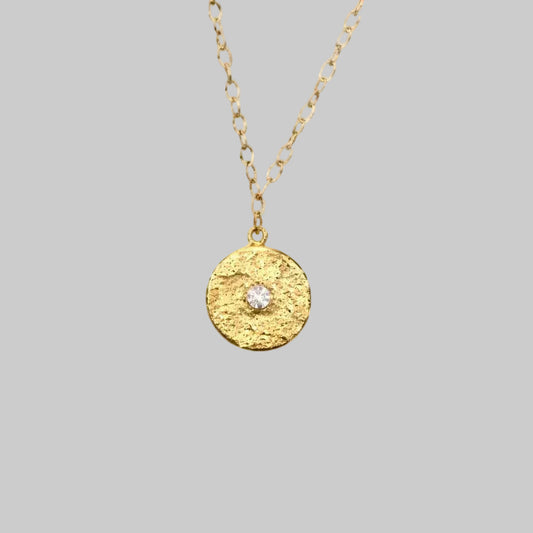 Textured Gold medallion with white topaz in the center