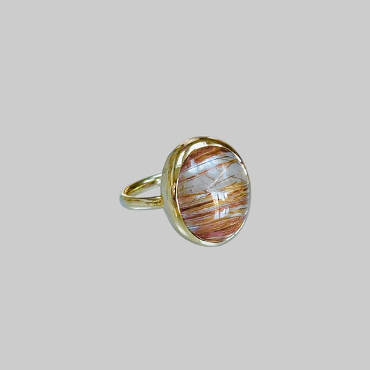 Gold ring with a golden rutilated quartz stone on a light gray background
