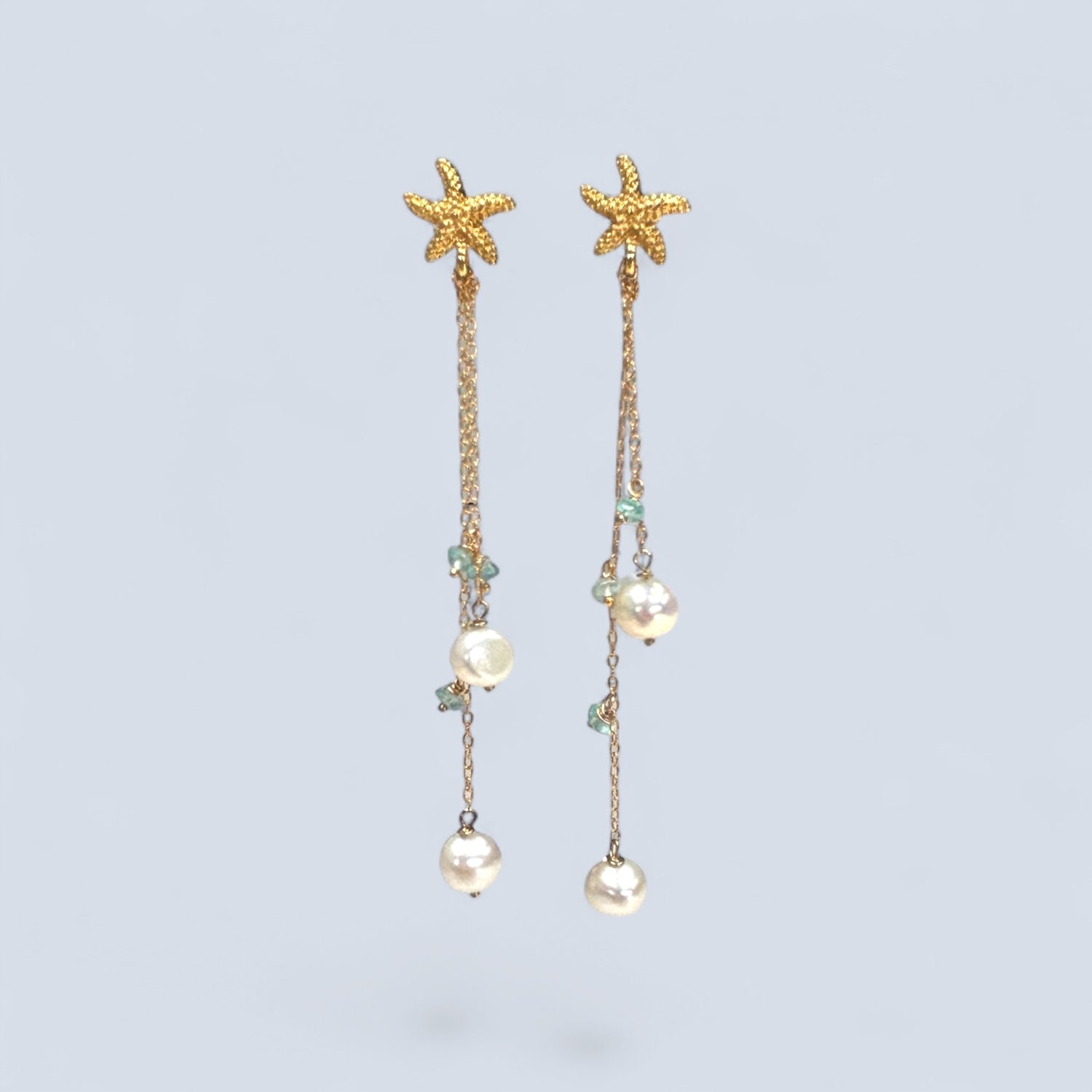Starfish and pearl drop earrings on a light blue background