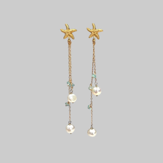 Starfish and pearl drop earrings on a light blue background