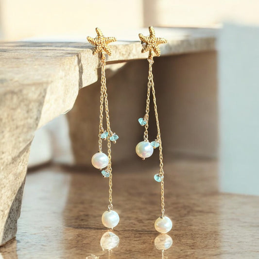 Starfish and pearl drop earrings on a neutral background