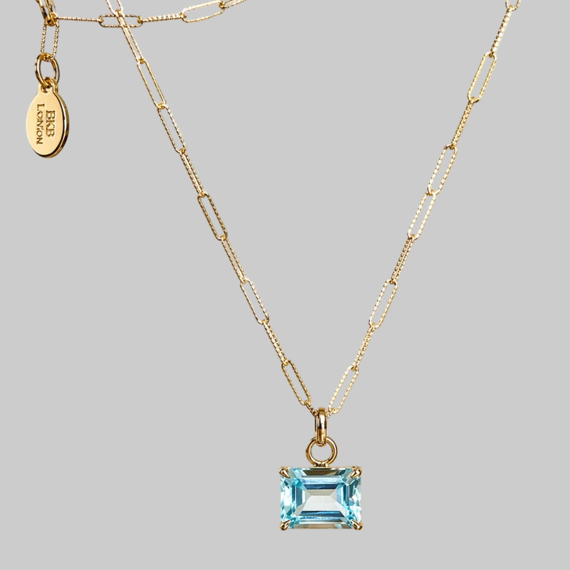 Emerald cut sky blue topaz pendant suspended from 16 inches paperclip style  chain in 9ct yellow gold 