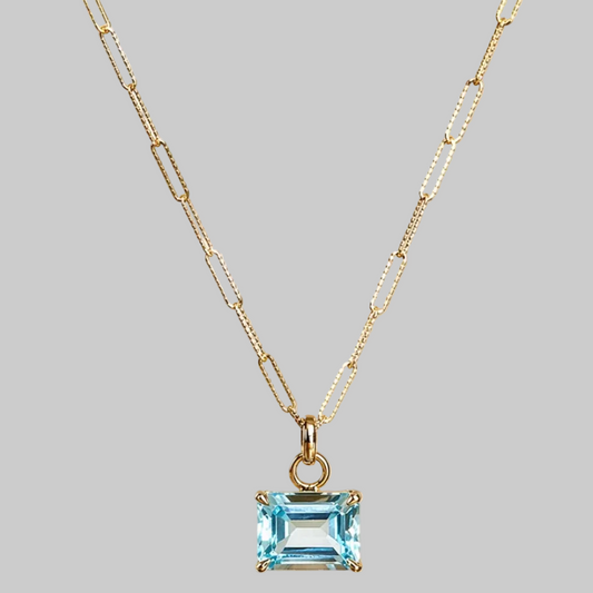 Emerald cut sky blue topaz pendant suspended from 16 inches paperclip style chain in 9ct yellow gold