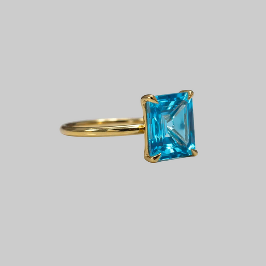 Yellow gold ring featuring large emerald cut topaz